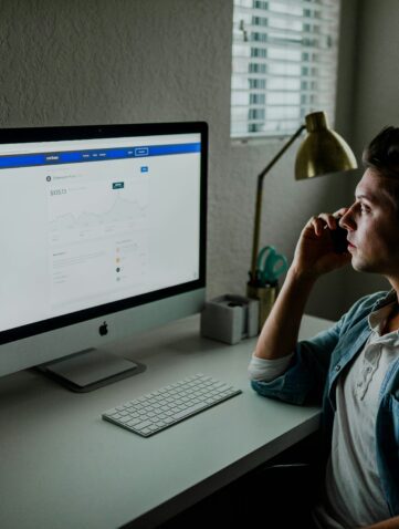 man in blue denim jacket facing turned on monitor